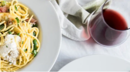 Italian noodle dish with red wine on white table cloth